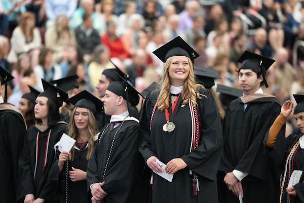 student at commencement, smiling in regalia
